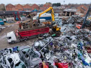 Scrap metal merchant's yard with a stack of crushed and damaged cars and metal