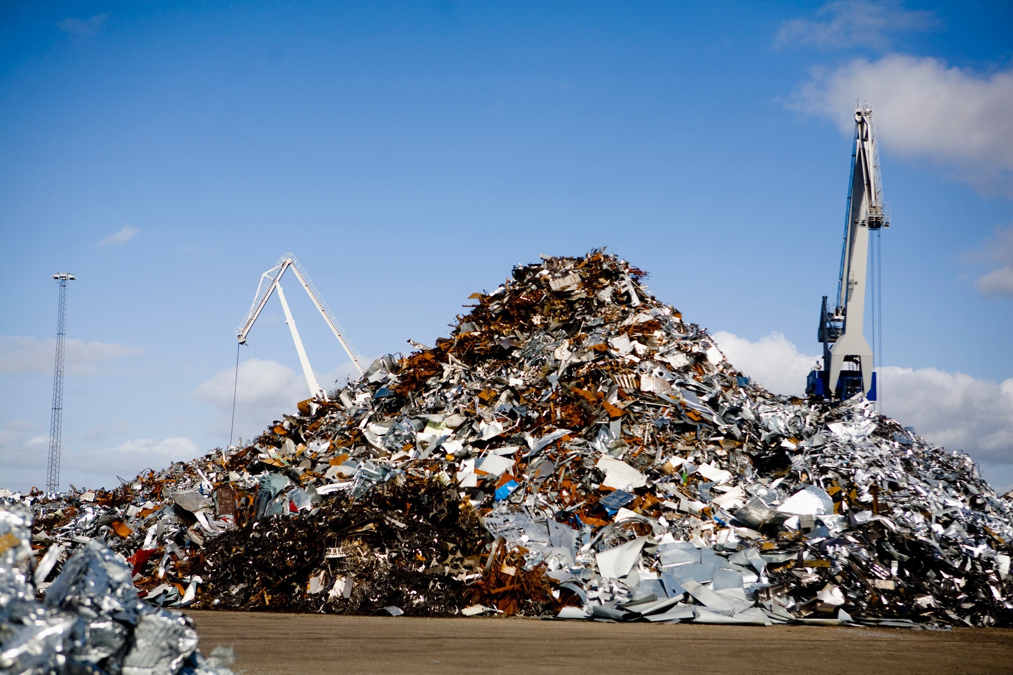 Heap of metal scrap at junkyard against blue sky